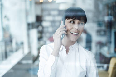 Businesswoman talking on smart phone at coffee shop - JOSEF04600