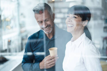 Smiling male and female entrepreneurs standing at coffee shop - JOSEF04605