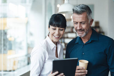 Female and male owners using digital tablet at coffee shop - JOSEF04608