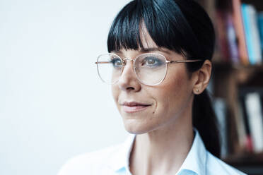 Businesswoman wearing eyeglasses looking away at cafe - JOSEF04609