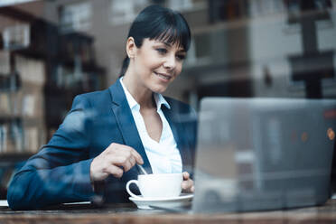 Lächelnde Unternehmerin mit Laptop in einem Cafe - JOSEF04628