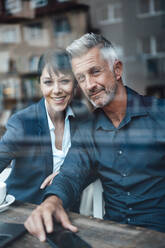 Business couple smiling while sitting at coffee shop - JOSEF04630