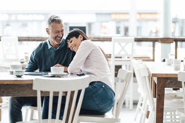 Happy business couple sitting together in cafe - JOSEF04686