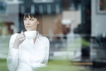 Geschäftsfrau trinkt Kaffee im Stehen in einem Cafe - JOSEF04701