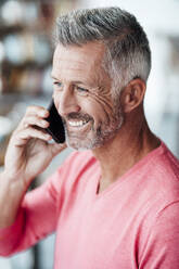 Smiling businessman talking on mobile phone at coffee shop - JOSEF04725