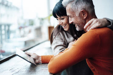 Mature couple using digital tablet in coffee shop - JOSEF04776