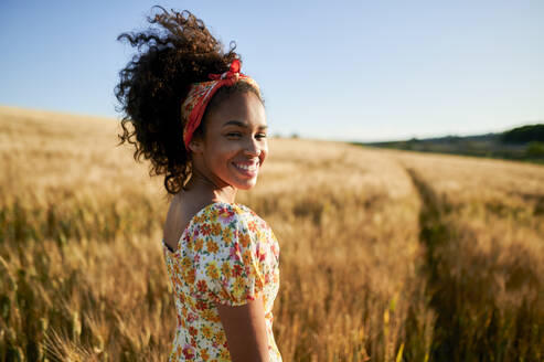 Happy beautiful woman with curly hair in wheat field - KIJF03919