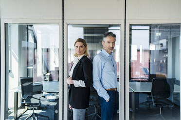 Male and female entrepreneurs standing together at doorway in office - DIGF15521