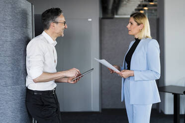 Geschäftsmann und Geschäftsfrau diskutieren im Büro stehend - DIGF15552