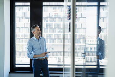 Male professional looking at white board while planning strategy in office - DIGF15607