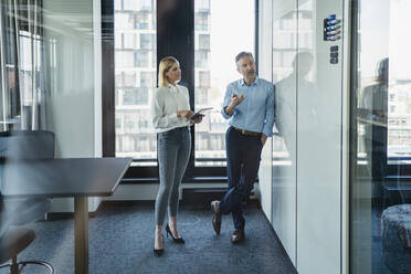 Männlicher Fachmann, der mit einer weiblichen Kollegin über eine weiße Tafel diskutiert, während er eine Strategie im Büro plant - DIGF15610