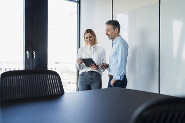 Männliche und weibliche Fachkräfte diskutieren über ein digitales Tablet im Büro - DIGF15615