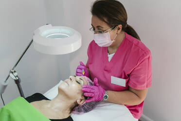 Female aesthetician giving biorevitalization treatment to woman at clinic - EGAF02390