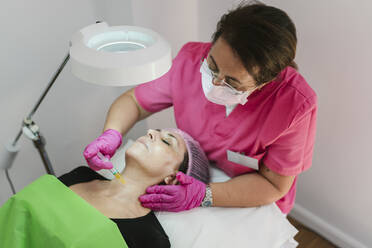 Aesthetician giving biorevitalization treatment to mature woman at clinic - EGAF02391