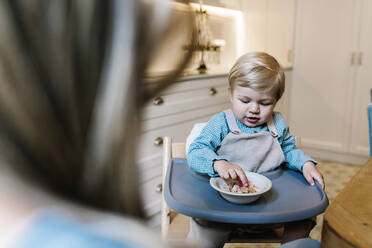 Kleiner Junge beim Essen vor der Mutter zu Hause - XLGF01921