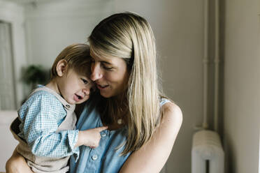 Pregnant woman talking with son while carrying at home - XLGF01932