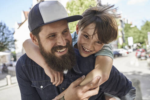 Playful son arm around father on street - AUF00677