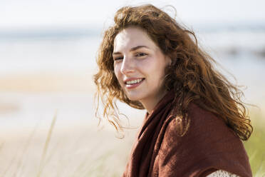 Schöne rothaarige Frau lächelnd am Strand während sonnigen Tag - SBOF03862