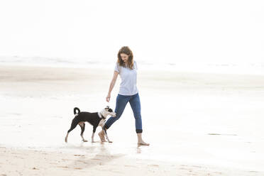 Frau mit Jack Russell Terrier bei einem Spaziergang am Strand - SBOF03890