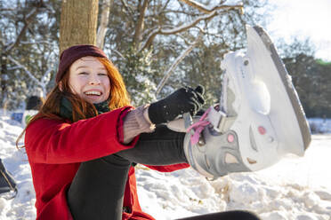 Smiling woman wearing ice skate during winter - FVDF00180