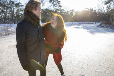 Happy couple standing on frozen lake during sunny day - FVDF00187
