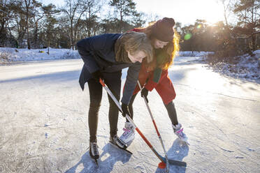 Freundin mit Freund spielt Eishockey auf einem zugefrorenen See - FVDF00190