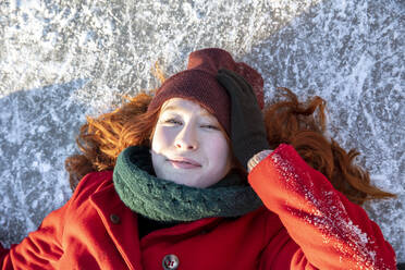 Beautiful woman wearing knit hat lying on ice - FVDF00194