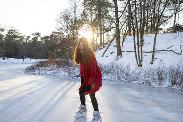 Excited woman ice-skating on frozen lake - FVDF00207