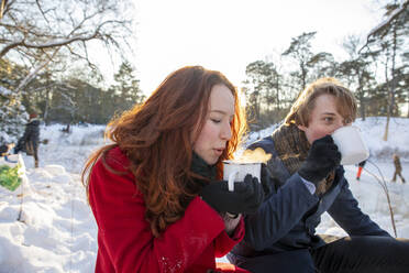 Girlfriend with boyfriend enjoying coffee during winter - FVDF00211