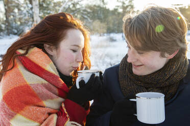 Girlfriend wrapped in shawl while drinking coffee with boyfriend - FVDF00212