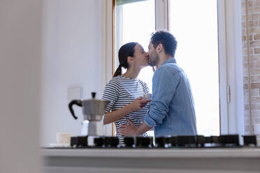 Pärchen küsst sich am Fenster in der Küche zu Hause - EIF01066