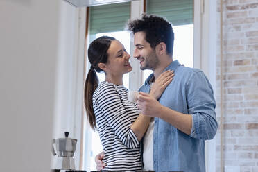 Happy affectionate couple with coffee cup in domestic kitchen - EIF01069