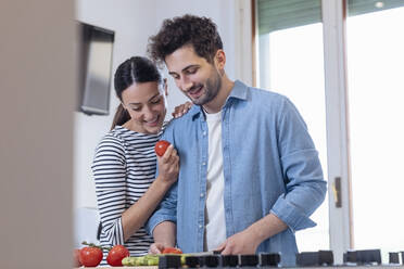 Smiling couple chopping food together in kitchen at home - EIF01082