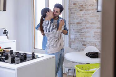 Smiling affectionate couple in domestic kitchen - EIF01093