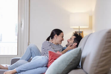 Happy girlfriend and boyfriend sitting on sofa in living room - EIF01099