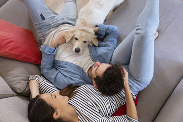 Paar und süßer weißer Hund lehnen sich auf dem Sofa aneinander - EIF01116