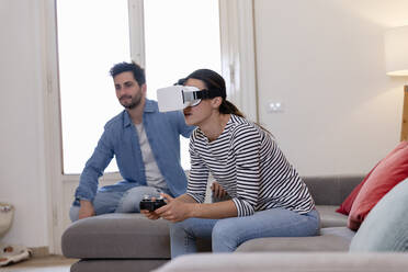 Junge Frau spielt mit Virtual-Reality-Simulator bei ihrem Freund zu Hause - EIF01128