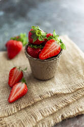 Tasse mit frischen, reifen Erdbeeren auf einem Platzdeckchen - GIOF12732