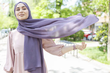 Junge Frau mit Hidschab, die im Park steht und wegschaut - IFRF00726