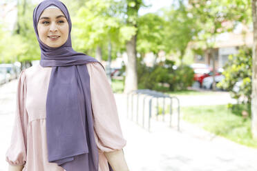 Junge Frau mit Hidschab, die im Park steht und wegschaut - IFRF00728