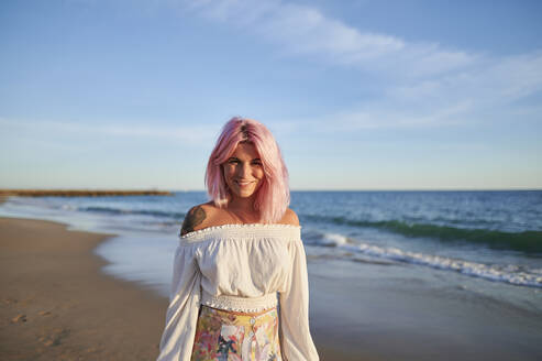 Lächelnde Hipster-Frau am Strand stehend an einem sonnigen Tag - KIJF03941
