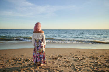 Woman looking at horizon while standing on shore during sunset - KIJF03943