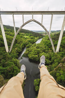Spanien, Provinz A Coruna, Vedra, Persönliche Perspektive eines Mannes, der über einem Tal sitzt, das den Fluss Ulla überspannt, mit der Gundian-Brücke im Hintergrund - RSGF00710