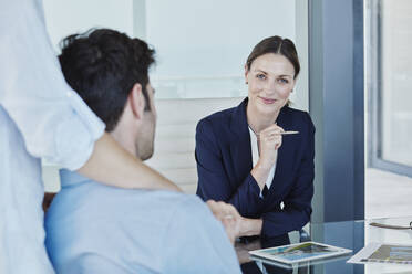 Lächelnde Geschäftsfrau im Gespräch mit einem männlichen und einem weiblichen Kunden - RORF02750