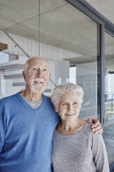 Senior couple standing together in front of glass wall - RORF02772