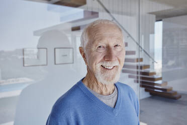 Smiling senior man standing in front of glass wall - RORF02778