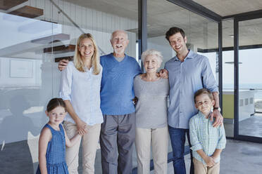 Happy multi-generation family standing together in front of glass wall - RORF02785