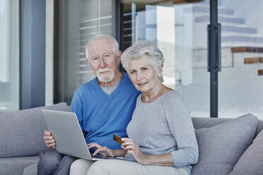 Älteres Paar benutzt Laptop beim Online-Shopping zu Hause - RORF02796