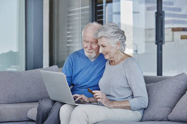 Senior man and woman using laptop while doing online shopping at home - RORF02798