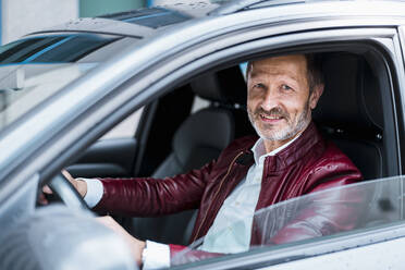 Smiling mature man wearing leather jacket driving car - DIGF15665